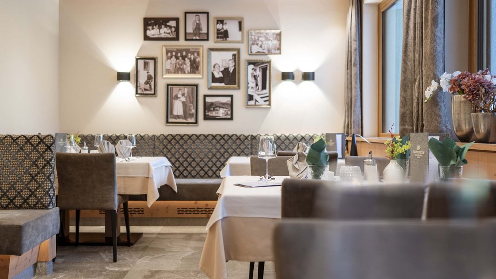 Smaragdhotel Tauernblick – Ihr 4-Sterne-Hotel am Wildkogel Gemütliches Restaurant mit Tischdekoration und Familienfotos an der Wand