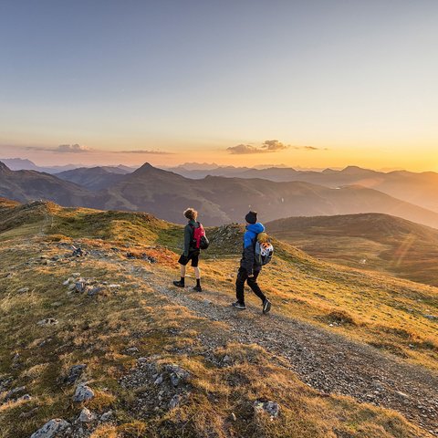 Family hotel in Bramberg: Smaragdhotel Tauernblick Two hikers with backpacks on mountain trail at sunset