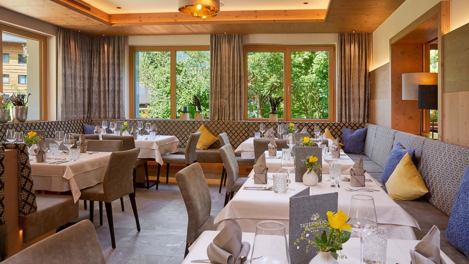 Salzburgerland: wellness hotel with 4 stars and cuisine Elegant restaurant with set tables and view of green trees outside windows