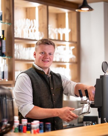 Wildkogel: Hotel mit Blick für das Besondere Junger Barkeeper zapft ein Getränk in einer modernen Bar