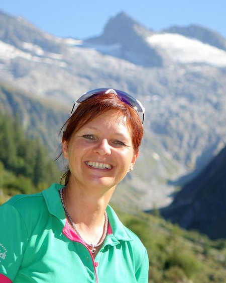 Hohe Tauern National Park: holiday for bikers Woman in green sportswear smiling with snowy mountains and forest behind