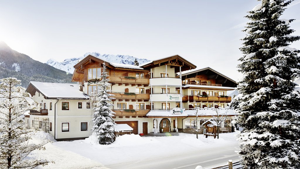Smaragdhotel Tauernblick – Ihr 4-Sterne-Hotel am Wildkogel Alpenhotel mit Holzbalkonen und schneebedeckten Dächern vor einer Bergkulisse
