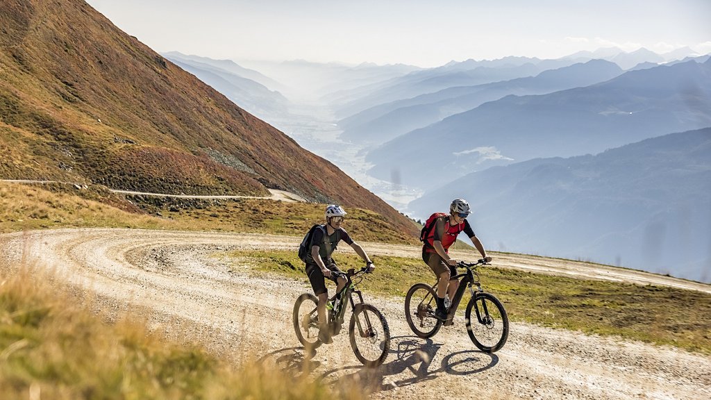 Nationalpark Hohe Tauern: Urlaub für Biker Zwei Radfahrer auf Bergstraße mit nebligen Bergen im Hintergrund