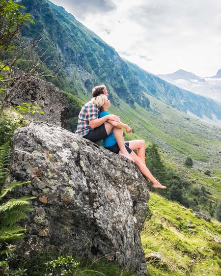 Your couples’ holiday in Austria Couple sitting on rock enjoying mountain view with valley and river