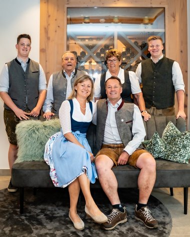 Wildkogel: Hotel mit Blick für das Besondere Familiengruppe in traditioneller Tracht sitzt in modernem Wohnzimmer