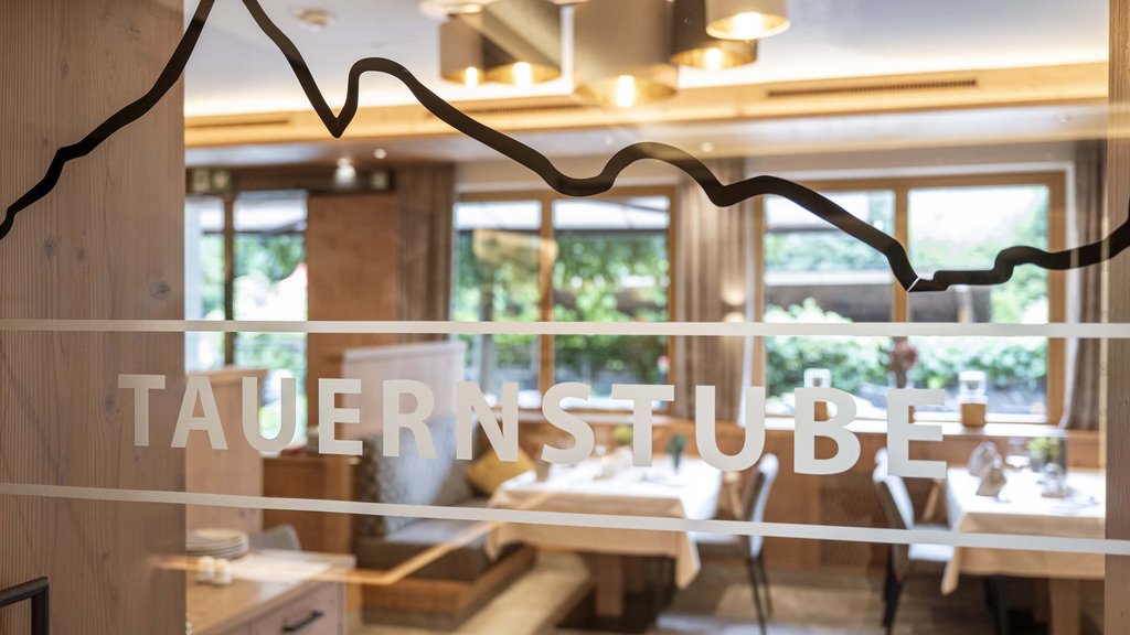 Salzburgerland: wellness hotel with 4 stars and cuisine Interior of a restaurant with Tauernstube sign on glass window