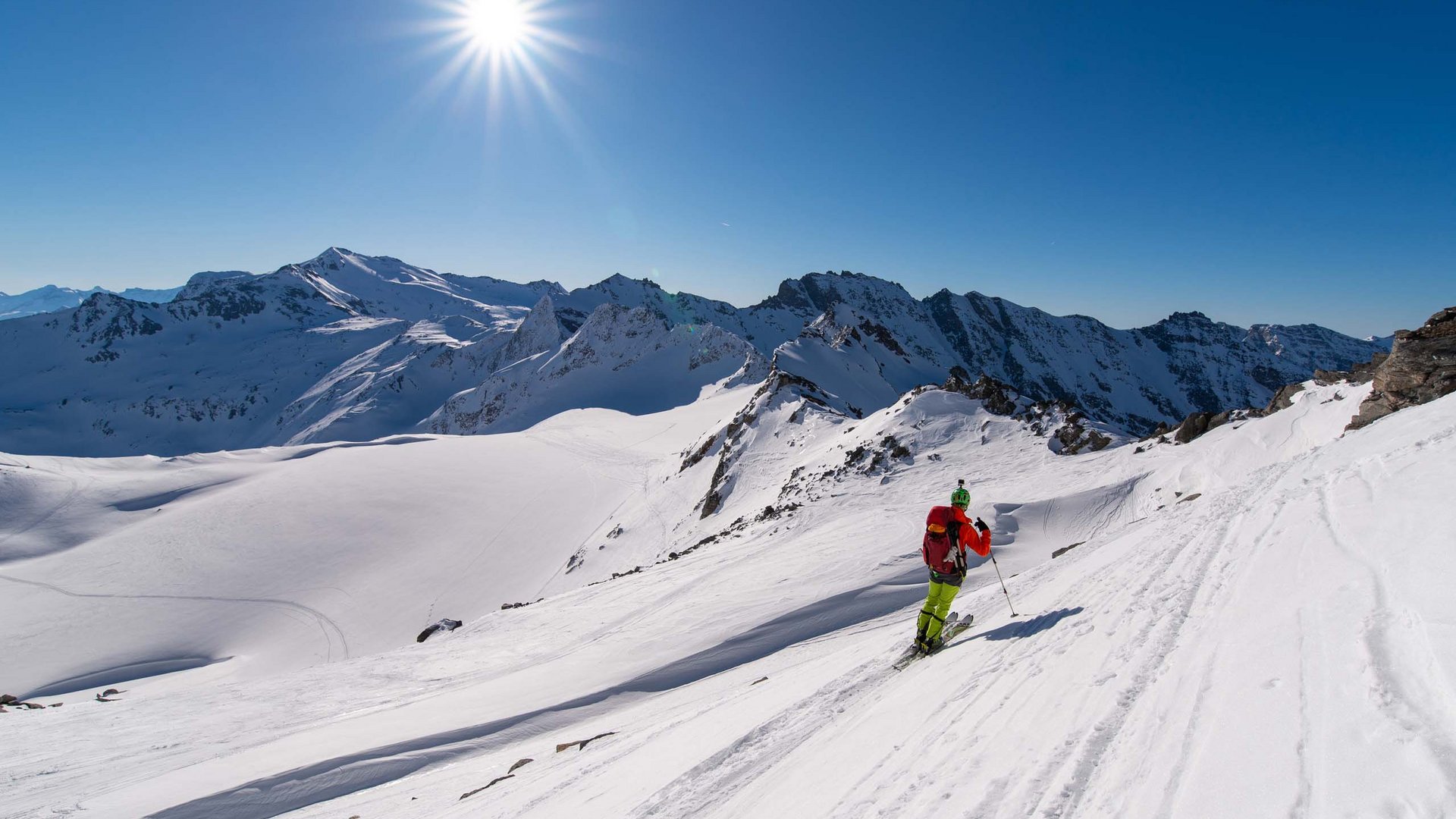 Smaragdhotel Tauernblick – your 4-star hotel near Wildkogel Skier in bright gear skiing down snowy slope with sun shining and clear blue sky