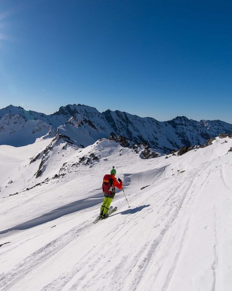 Salzburgerland: Winter im Smaragdhotel Tauernblick Skifahrer in bunter Ausrüstung fährt auf schneebedecktem Hang unter Sonne und blauem Himmel