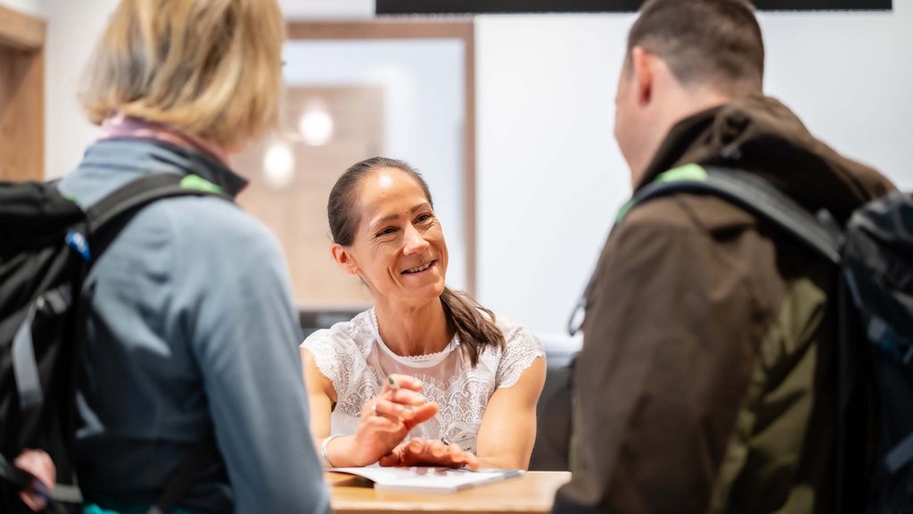 Ihr Pärchenurlaub in Österreich Frau gibt Reisenden an Rezeption Informationen