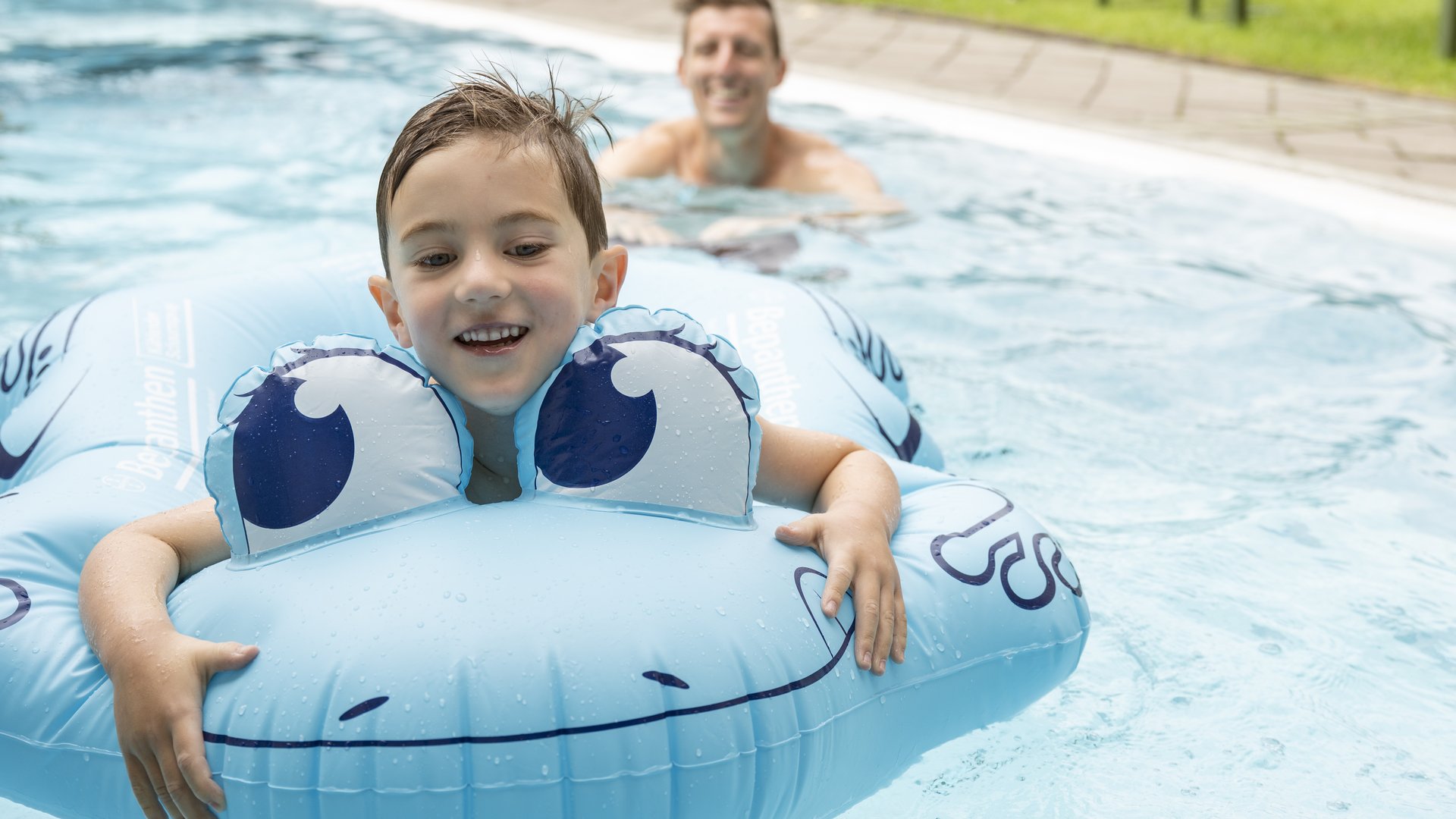 Smaragdhotel Tauernblick – Ihr 4-Sterne-Hotel am Wildkogel Junge mit blauem Tier-Schwimmreifen und Mann im Pool im Hintergrund